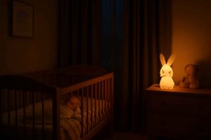 Bebê dormindo em berço com luz noturna âmbar e cortinas blackout